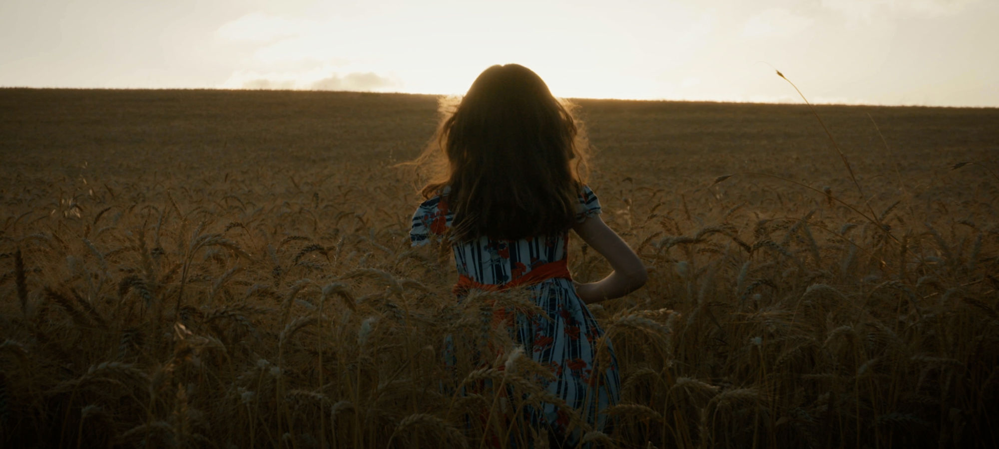 Girl in wheat field during sunset